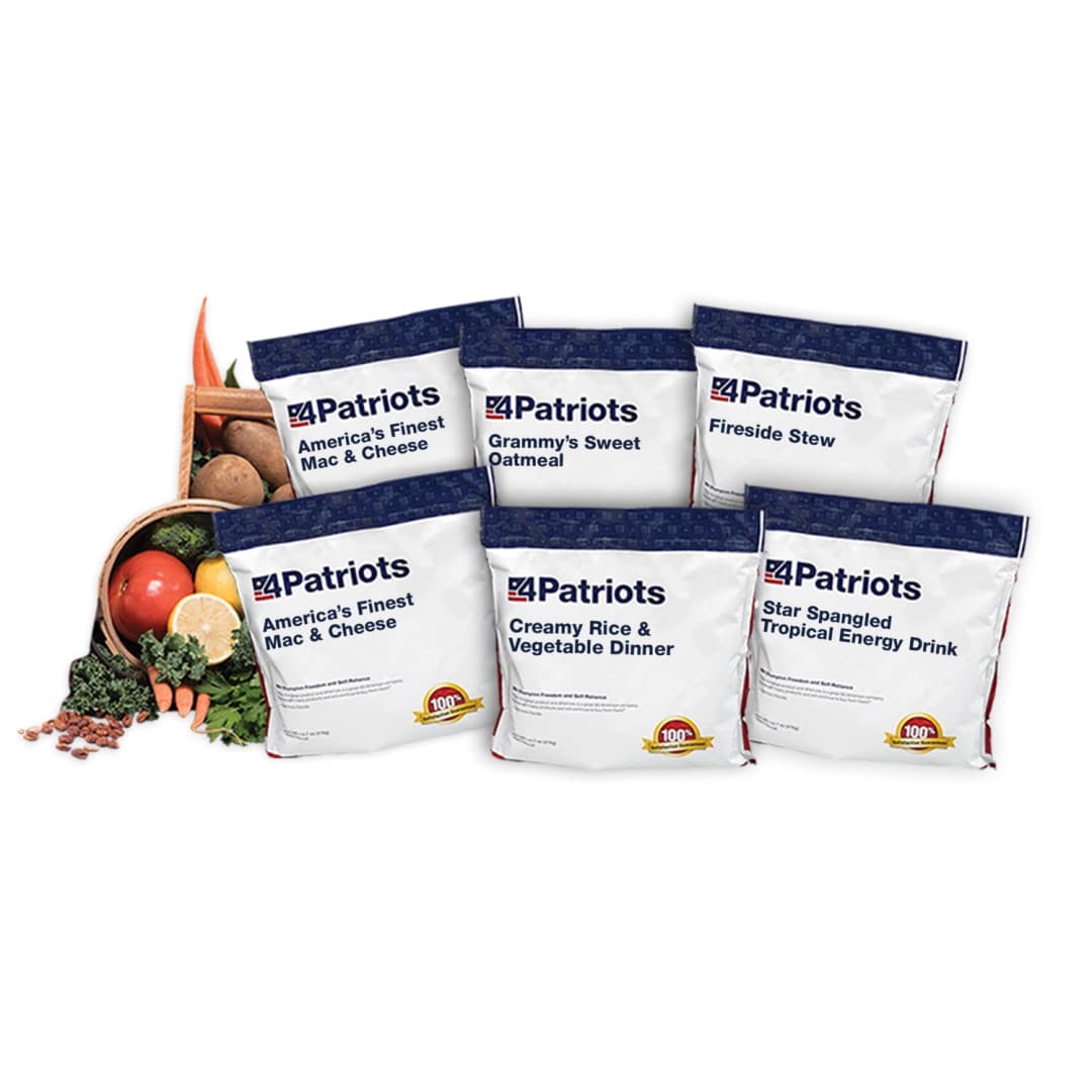 A display of five white and navy emergency food pouches from 4Patriots, arranged in front of a tipped-over basket of fresh vegetables. Pouches are labeled: “America’s Finest Mac & Cheese,” “Grammy’s Sweet Oatmeal,” “Fireside Stew,” “Creamy Rice & Vegetable Dinner,” and “Star Spangled Tropical Energy Drink.” The basket includes carrots, kale, apples, and potatoes, highlighting the wholesome ingredients used.