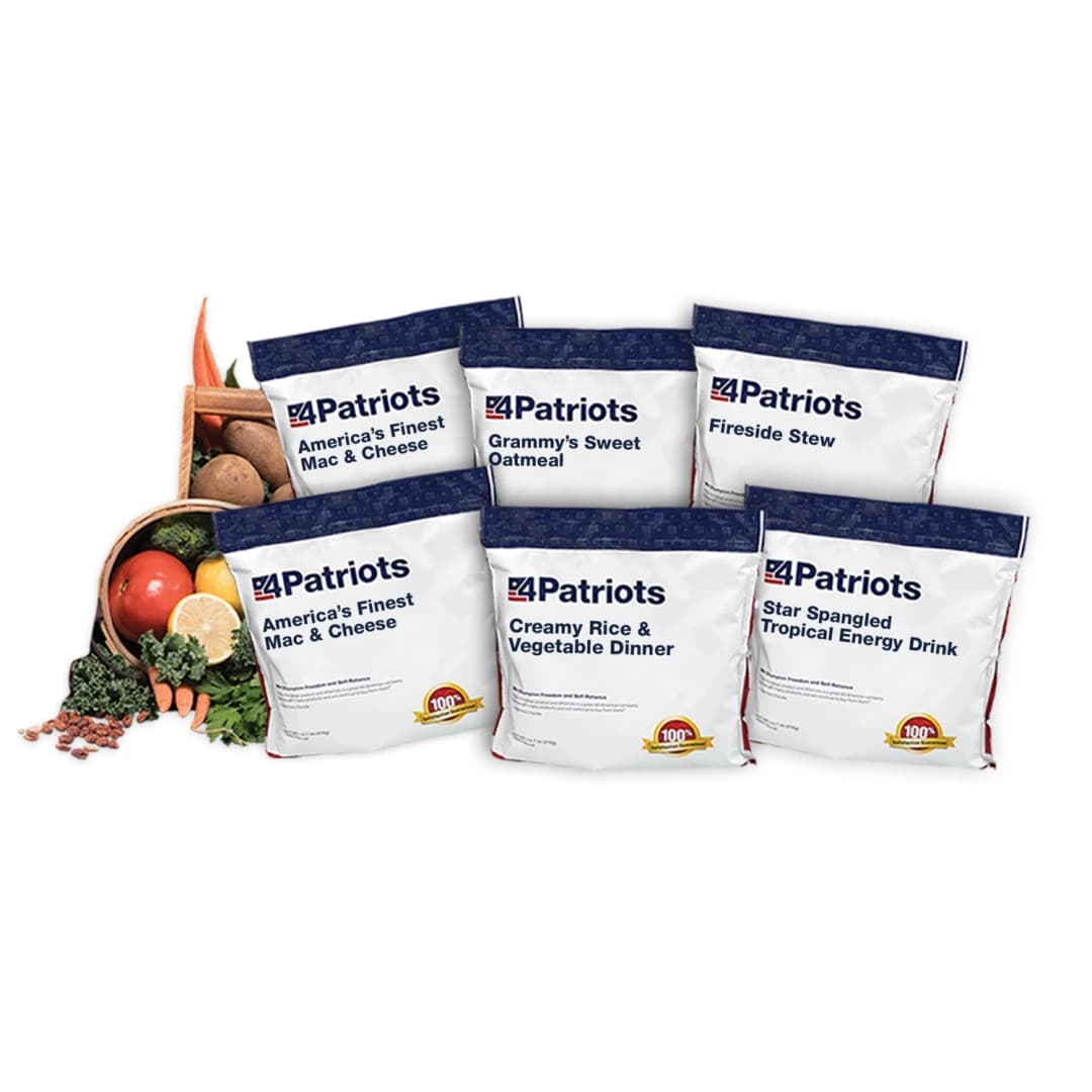 A display of five white and navy emergency food pouches from 4Patriots, arranged in front of a tipped-over basket of fresh vegetables. Pouches are labeled: “America’s Finest Mac & Cheese,” “Grammy’s Sweet Oatmeal,” “Fireside Stew,” “Creamy Rice & Vegetable Dinner,” and “Star Spangled Tropical Energy Drink.” The basket includes carrots, kale, apples, and potatoes, highlighting the wholesome ingredients used.