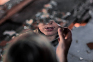 A woman's reflection caught in a broken mirror on the ground