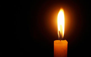 A single lit candle flame against a black background