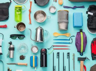 An overhead flat lay of camping and survival gear on a teal background