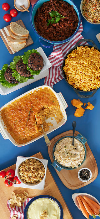 Vertical flat lay of 4Patriots 1-Year Survival Food Kit survival meals on blue: chili, mac and cheese, sliders, casserole and seasoned rice