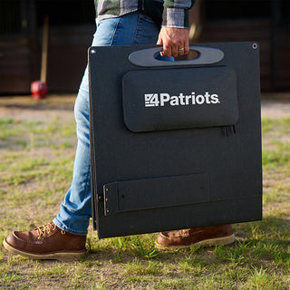 Close-up of the folded 200-Watt Portable Folding Solar Panel with 4Patriots pouch being carried by hand across a farm, portable off-grid emergency power