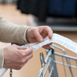 3-Month Emergency Survival Food Kit context image of a shopper examining a long grocery store receipt over a cart, evoking rising food prices and the value of long-term food storage for preparedness