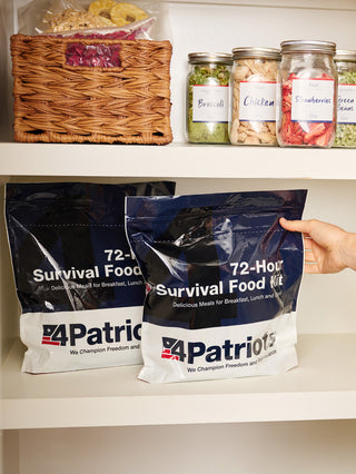 Hand grabbing one of two 72-Hour Emergency Survival Food Kit pouches on a pantry shelf with freeze-dried food jars, emergency food supply