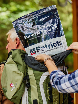 72-Hour Emergency Survival Food Kit being packed into a hiking backpack outdoors by a couple, compact survival food for camping and preparedness