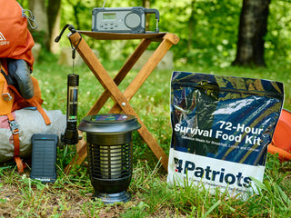 72-Hour Emergency Survival Food Kit pouch grouped with a backpack, radio, lantern and power bank on grass, camping and disaster preparedness food