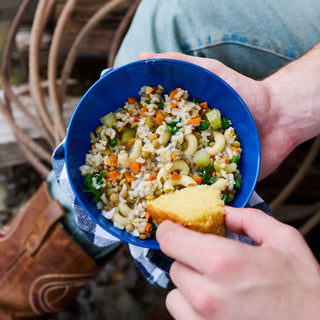 Hands holding a blue bowl of prepared Buckaroo Stew with cornbread, a 72-Hour PlatinumXL Emergency Survival Food Kit meal, survival food