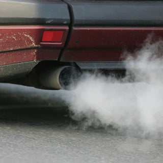 Thick exhaust fumes pouring from an old car tailpipe, a reminder to keep a 72-Hour PlatinumXL Emergency Survival Food Kit on hand for disaster preparedness