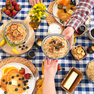 Overhead breakfast table of Country Griddle Breakfast Kit oatmeal, blueberry pancakes and syrup shared on a blue gingham cloth