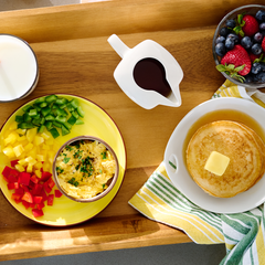 Delicious breakfast meal on a food platter including scrambled eggs, pancakes, and fruit.
