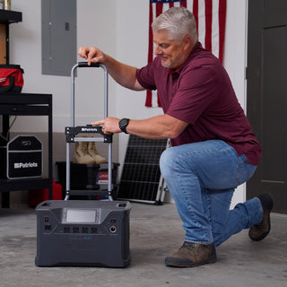 Man kneels to extend the telescoping handle on the Roll & Go Foldable Generator Cart with a 4Patriots portable power station loaded on the platform