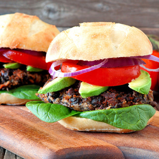 4Patriots Black Bean Burger Mix Case Pack served as two black bean burgers with avocado, tomato and onion on a board, tasty survival food meal