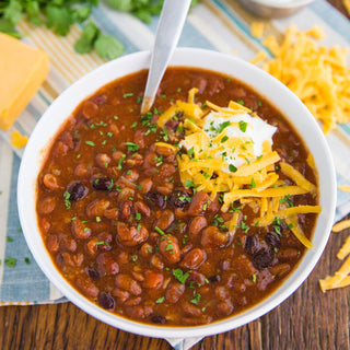 Classic Bean Chili Case Pack prepared in a white bowl topped with shredded cheddar, sour cream and parsley, a hearty survival food meal