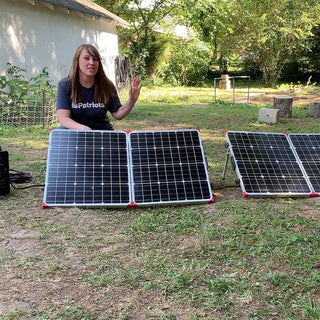 25-Foot Solar Panel Extension Cord daisy-chaining two folding solar panels as a woman sets up a portable solar generator in a sunny backyard