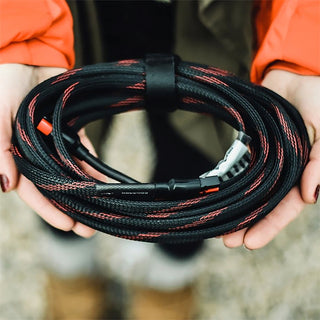 25-Foot Solar Panel Extension Cord held coiled in a person's hands outdoors, showing the rugged braided sleeve for solar generator use