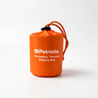 Orange 4Patriots Emergency Thermal Sleeping Bag packed in a small drawstring stuff sack with a black cord lock