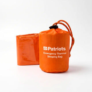 Orange 4Patriots Emergency Thermal Sleeping Bag in a drawstring stuff sack, with the folded orange bag beside it.
