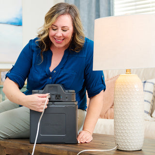 Woman plugging a lamp into the Expansion Battery Pack mounted on her Patriot Power Generator at home