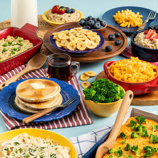 Family Emergency Essentials Package meals prepared on a table: pancakes, mac and cheese, oatmeal with berries, banana chips and broccoli from the survival food kit