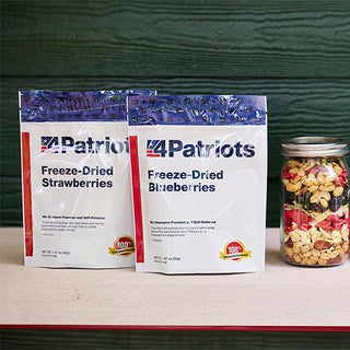 Freeze-Dried Strawberries and Blueberries pouches from the Family Favorites Emergency Survival Food Package beside a mason jar of trail mix at a cabin.