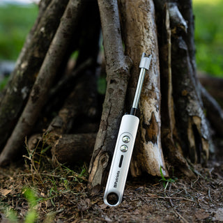 4Patriots Freedom Flame Rechargeable Flexible Arc Lighter leaning against a teepee of logs outdoors, a flameless survival fire starter