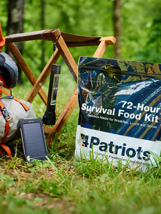 Food, Power & Light Emergency Go-Bag Starter Package staged outdoors with backpacking gear, showing the 72-hour survival food pouch, solar power bank and tactical flashlight for preparedness