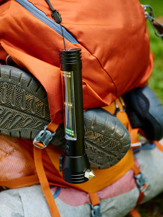 Food, Power & Light Emergency Go-Bag Starter Package HXT tactical solar flashlight clipped to an orange hiking backpack with boots, a rugged off-grid survival light for the go-bag