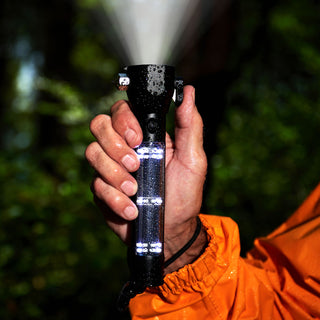 Food, Power & Light Emergency Go-Bag Starter Package HXT tactical solar flashlight shining brightly in a man's hand during rain, proving reliable emergency lighting for survival preparedness