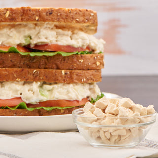 Freeze-Dried Chicken #10 Can rehydrated into a chicken salad sandwich beside a glass bowl of dried chicken pieces, survival food