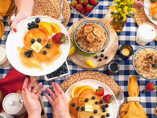 Gold Reserve Emergency Survival Package: 4-Week kit breakfast flatlay with hands passing a plate of pancakes and oatmeal, emergency food supply