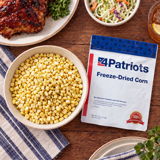Freeze-Dried Corn Pouch flatlay with a bowl of sweet corn kernels, grilled barbecue chicken, coleslaw and iced tea on a wooden table, emergency food supply