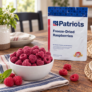 Freeze-Dried Raspberries Pouch standing behind a white bowl heaped with freeze-dried raspberries on a striped napkin with fresh mint, survival food snack