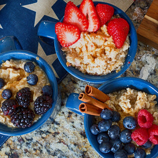 Grammy's Sweet Oatmeal Pouch served in three blue mugs of oatmeal topped with berries and cinnamon on a patriotic cloth, survival food breakfast.
