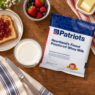 Heartland's Finest Powdered Whey Milk Pouch flat-lay with a glass of milk, jam toast, fresh berries and butter on a wooden table, emergency food supply