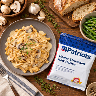 Hearty Stroganoff Pouch flatlay with a gray plate of creamy noodles, whole mushrooms, garlic, fresh thyme, sourdough bread and green beans, emergency food