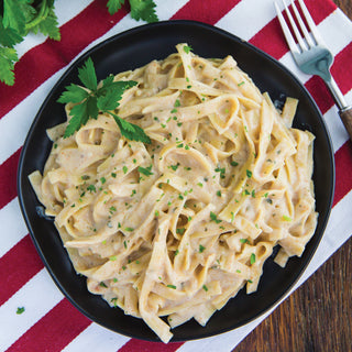 Hearty Stroganoff Pouch prepared as creamy noodles on a black plate garnished with parsley, ready-to-eat survival meals