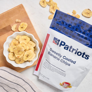 Sweetly-Coated Banana Chips Pouch flatlay of a wooden bowl of banana chips with fresh bananas on gray linen, lightweight portable survival food snack