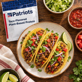 Taco-Flavored Plant-Based Protein Pouch overhead with a plate of three hard-shell tacos, diced tomato, cilantro and onion, salsa, lettuce and lime wedges, survival meals