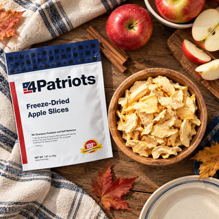 Freeze-Dried Apple Slices Pouch flatlay with a wooden bowl of apple chips, red apples, cinnamon sticks and autumn maple leaves, an emergency food supply snack