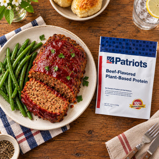 Overhead of Beef-Flavored Plant-Based Protein Pouch beside ketchup-glazed meatloaf with green beans, biscuits and iced lemon water on wood, emergency food