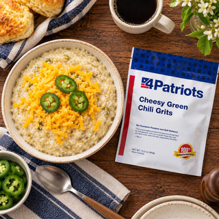 Cheesy Green Chili Grits Pouch flat-lay beside a bowl of grits topped with cheddar and jalapeno slices, with biscuits and coffee, an emergency food breakfast
