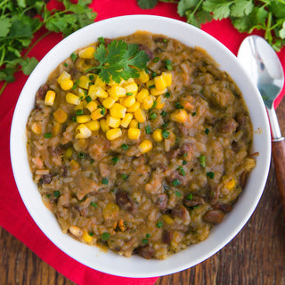 Cowboy Rice & Beans Pouch beside a bowl of rice and beans topped with corn and parsley with jalapeno slices, a delicious survival food meal