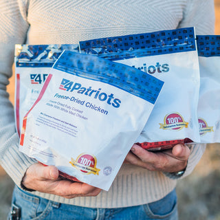 Gold Medallion All-Meat Emergency Survival Kit held outdoors by a man carrying 4Patriots freeze-dried chicken and beef pouches for emergency preparedness and survival food