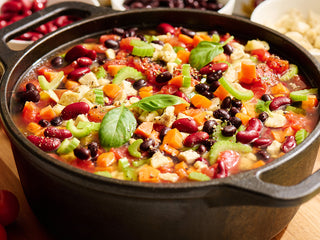 Cast iron pot of hearty bean and chicken chili cooked from the Meat & Protein Deluxe Emergency Survival Food Kit with carrots, celery and tomato