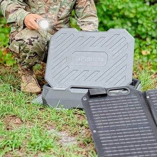 AlphaCase Elite: rugged black 4Patriots hard-shell power case opened outdoors with a folding solar panel as a soldier in camo holds a flashlight, off-grid emergency backup power