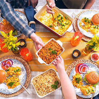 Overhead family table of prepared 4Patriots survival food kit dishes including cheesy rice casserole, beefy rice and mac and cheese being passed around