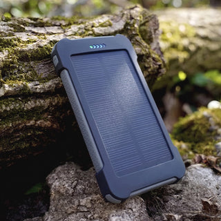 4Patriots Patriot Power Cell solar phone charger propped against a mossy log in the woods, a best-selling pocket solar power bank for camping and emergencies