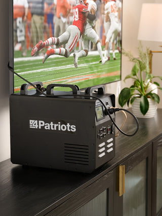 Patriot Power Solar Generator 1800 on a living room console running a wall-mounted TV during a blackout, portable solar generator for home emergency backup power
