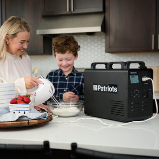 Patriot Power Solar Generator 1800 on a kitchen counter powering a hand mixer as a mom and son bake, portable solar generator for off-grid emergency backup power
